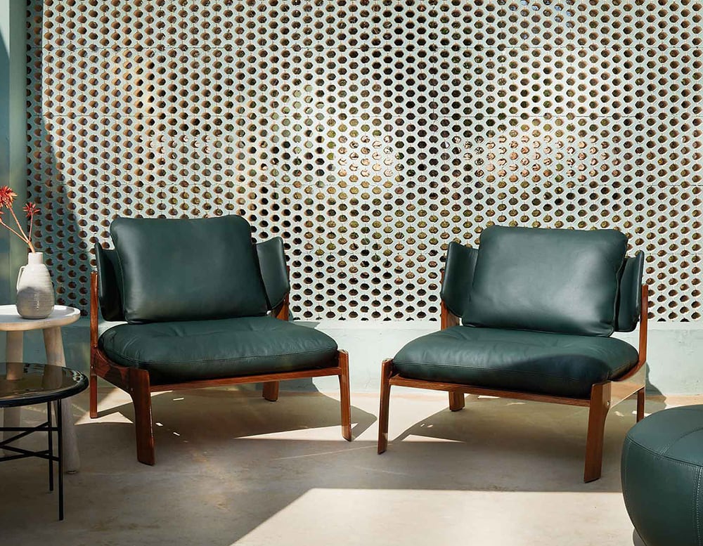 armchair upholstered in green leather and wooden bases in front of a fence